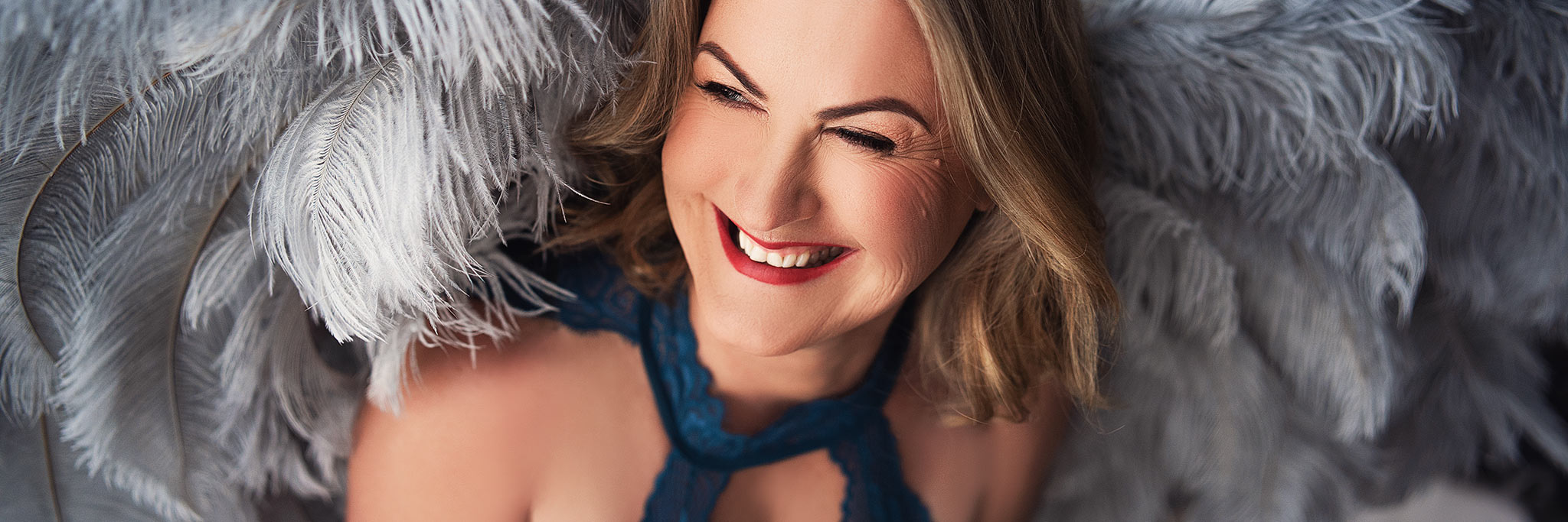 a woman smiling with feathers behind her gold coast photography reviews