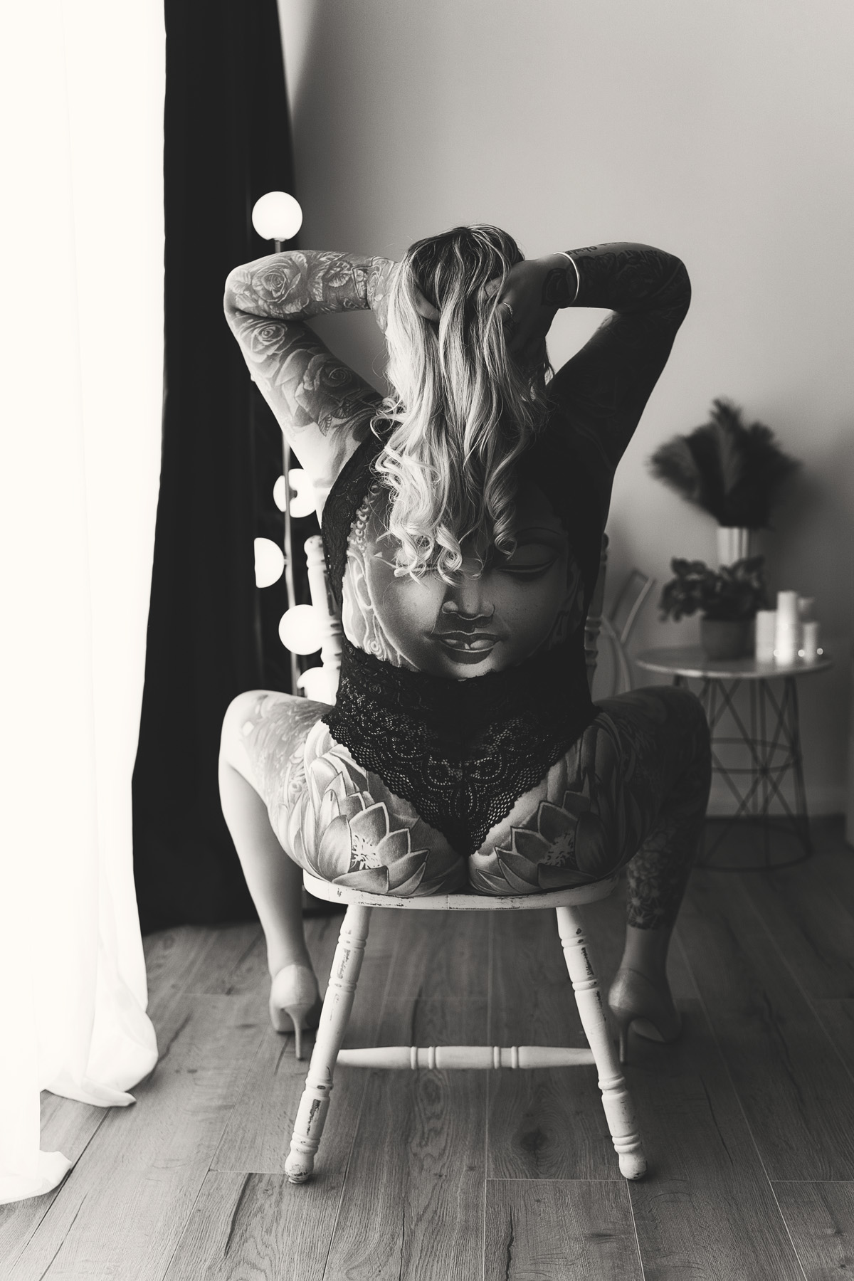 Boudoir client on chair, displaying back tattoos. Black and white photo, Photography session in Upper Coomera.