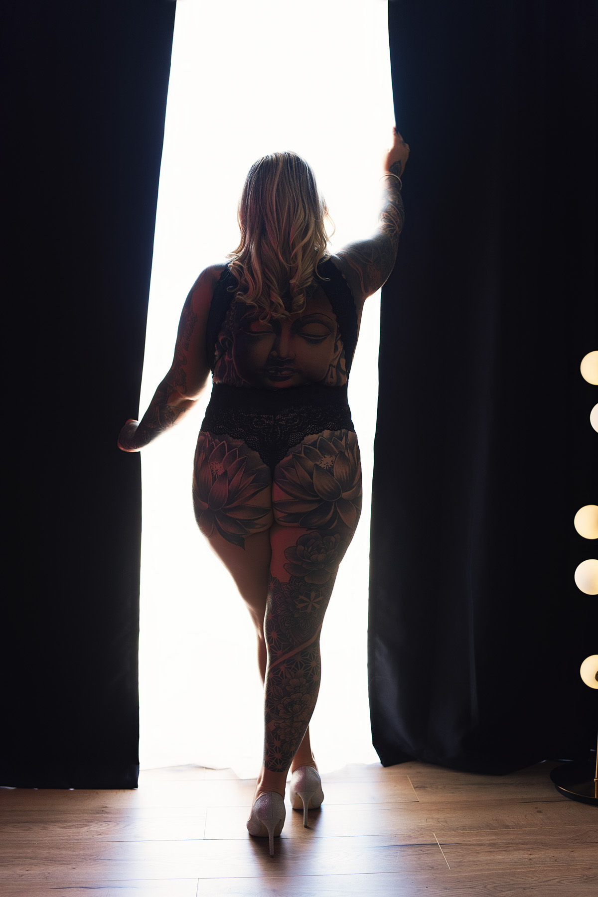 Woman with tattoos standing as a silhouette in boudoir studio on the Gold Coast.