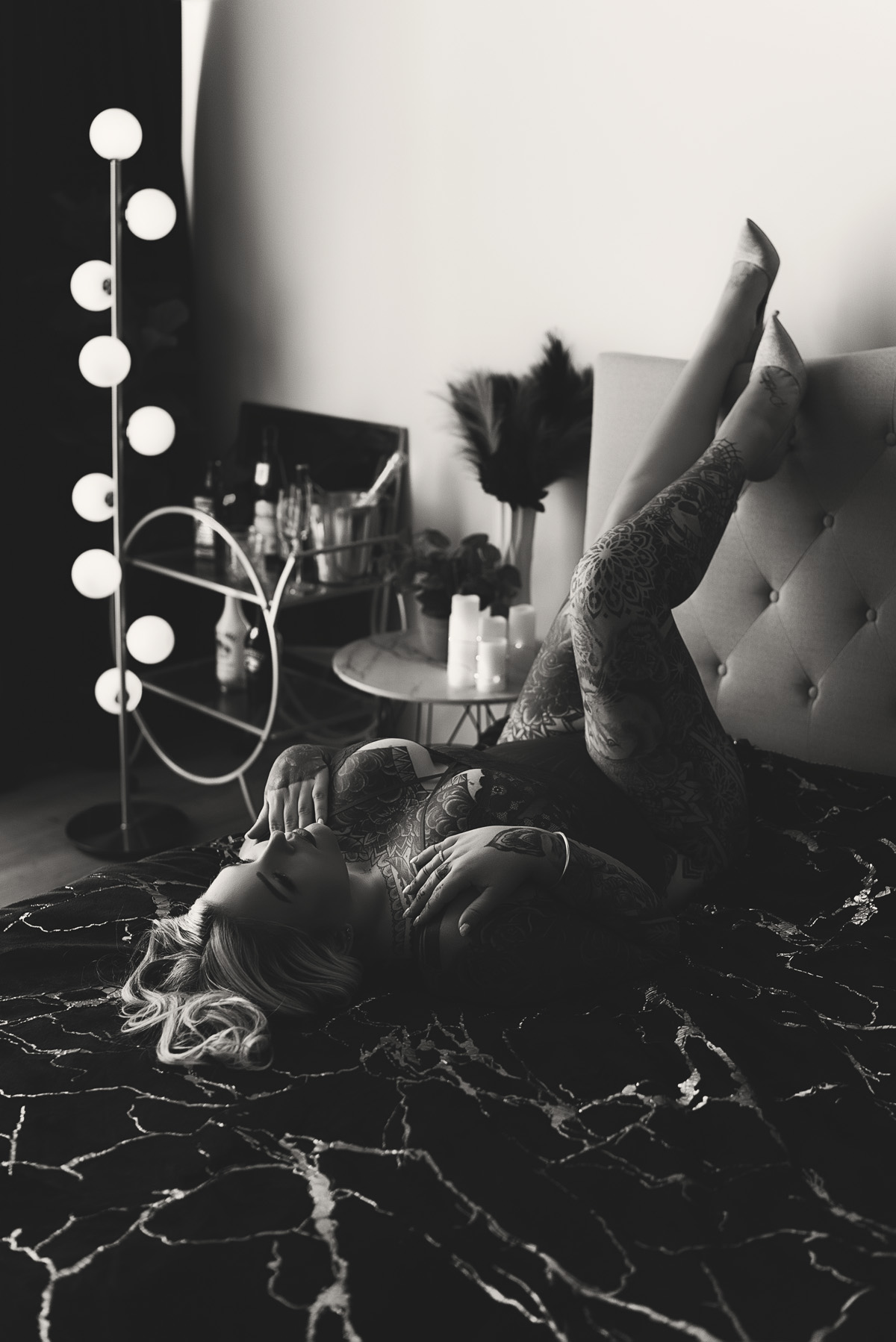 Boudoir client with tattoos lying on bed in black and white photo. Intimate photography on the Gold Coast.